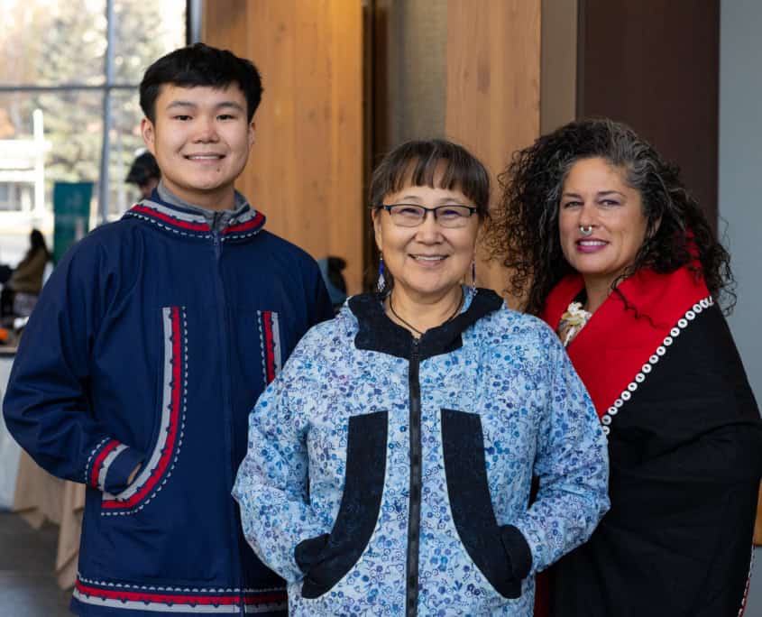 A group of people smiling and wearing traditional Alaska Native regalia