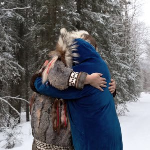 Two people hugging while standing on a snowy trail Two people hugging while standing on a snowy trail